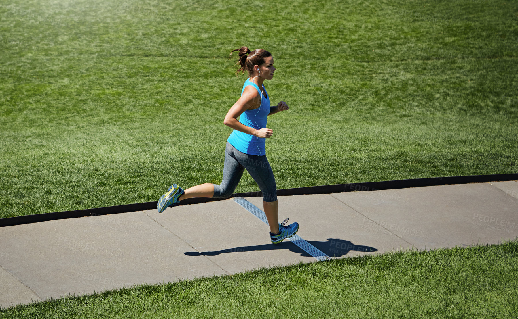 Buy stock photo Shot of a young woman listening to music while out running