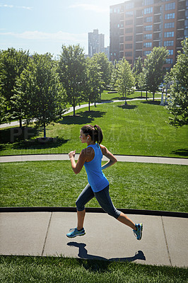 Buy stock photo Shot of a young woman listening to music while out running