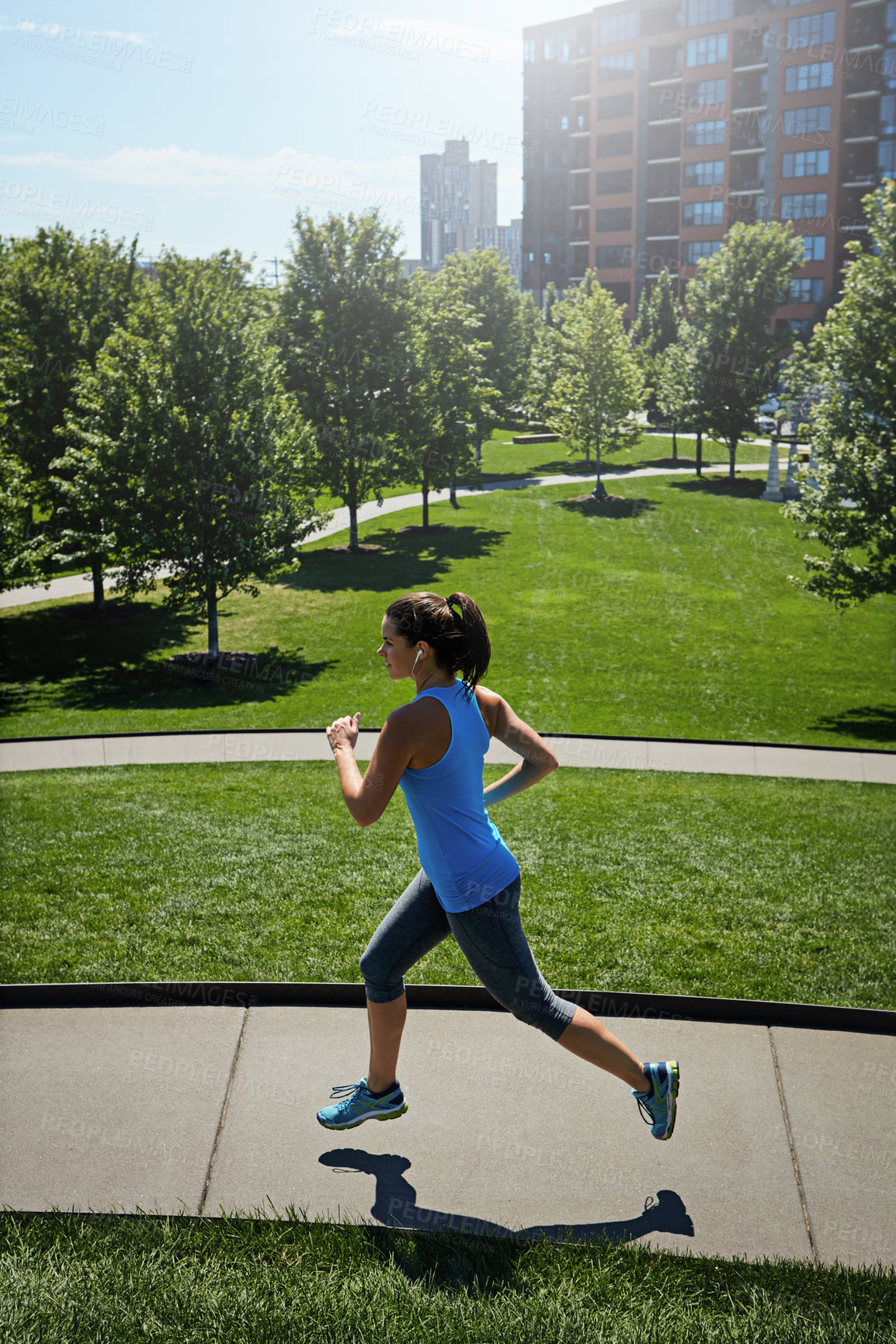 Buy stock photo Shot of a young woman listening to music while out running