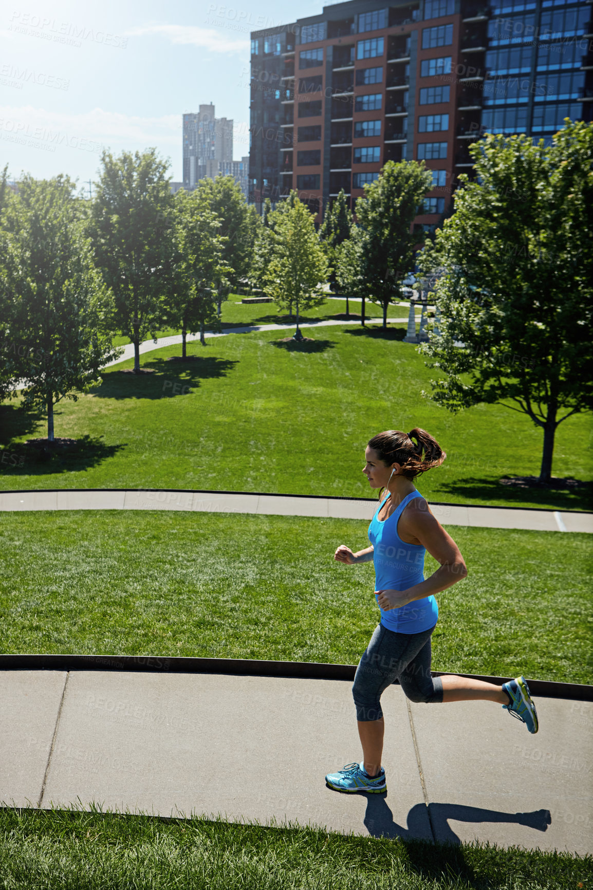 Buy stock photo Shot of a young woman listening to music while out running