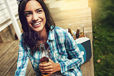Buy stock photo Shot of a young woman enjoying a beer outdoors