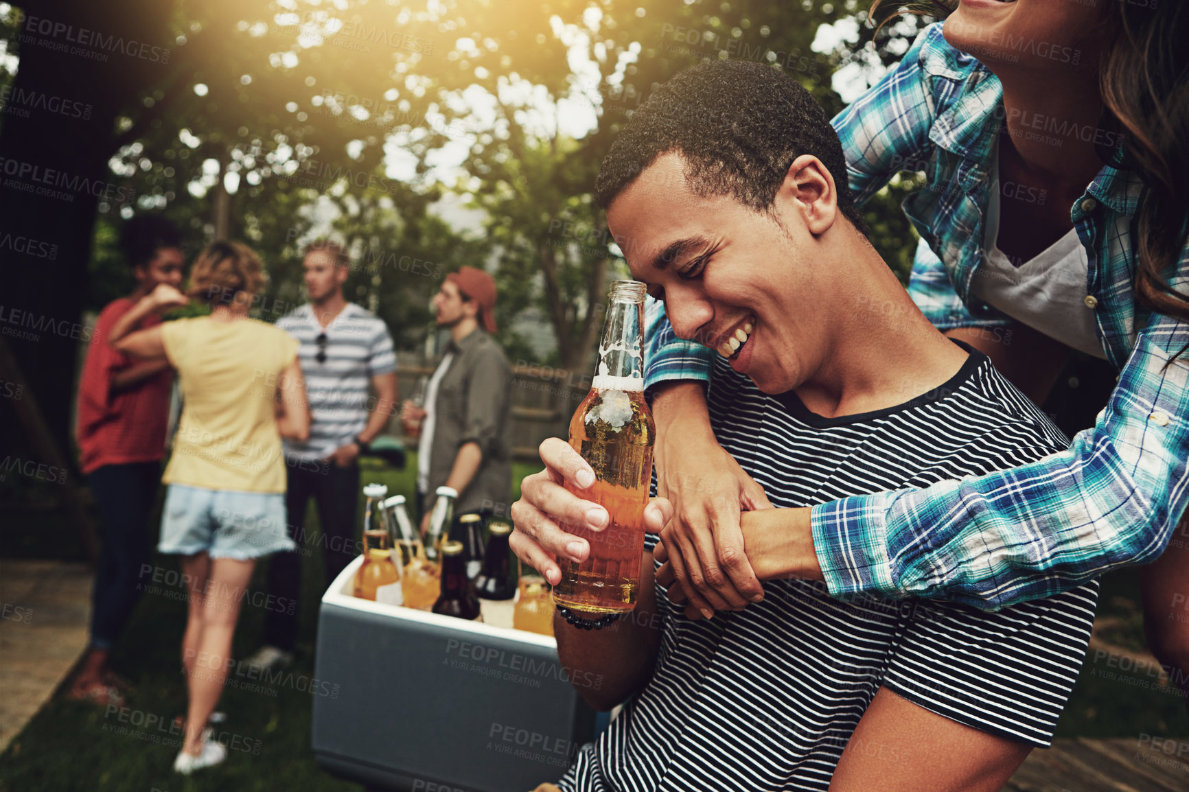 Buy stock photo Shot of a young couple enjoying a party with friends outdoors