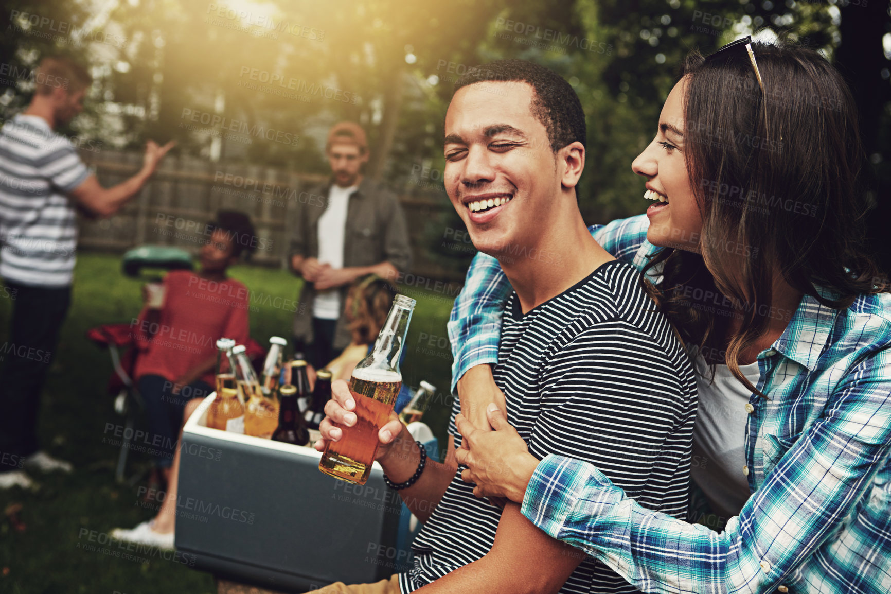 Buy stock photo Shot of a young couple enjoying a party with friends outdoors