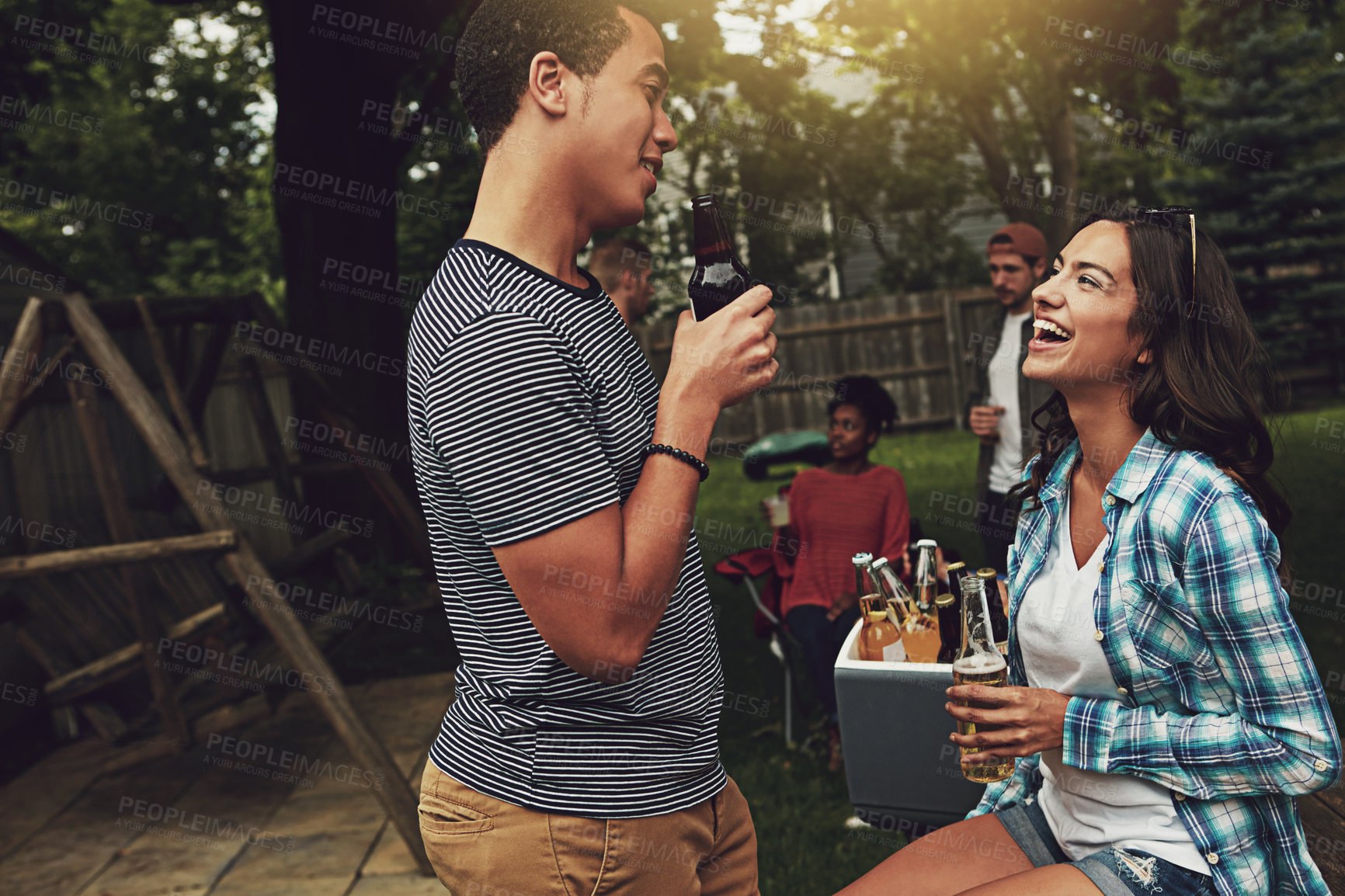 Buy stock photo Shot of a young man and woman chatting at a party outdoors