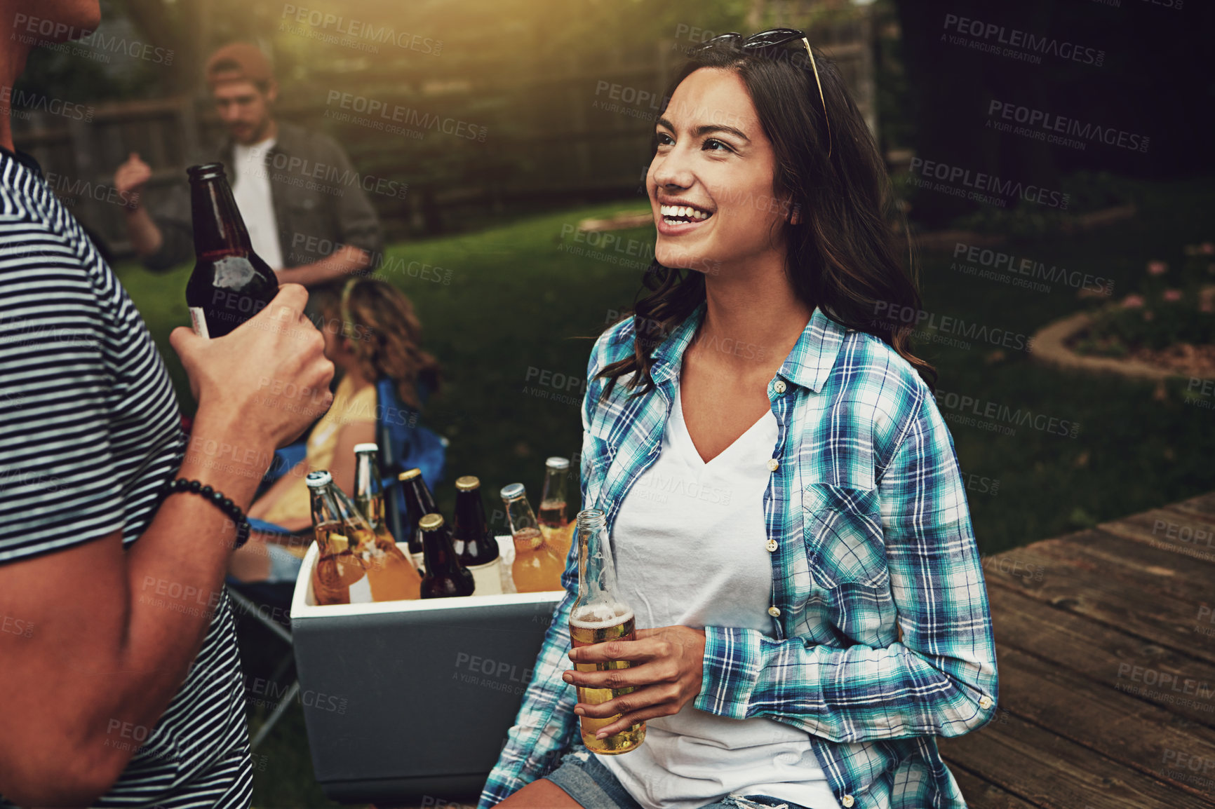 Buy stock photo Shot of a young woman chatting to a friend at a party outdoors
