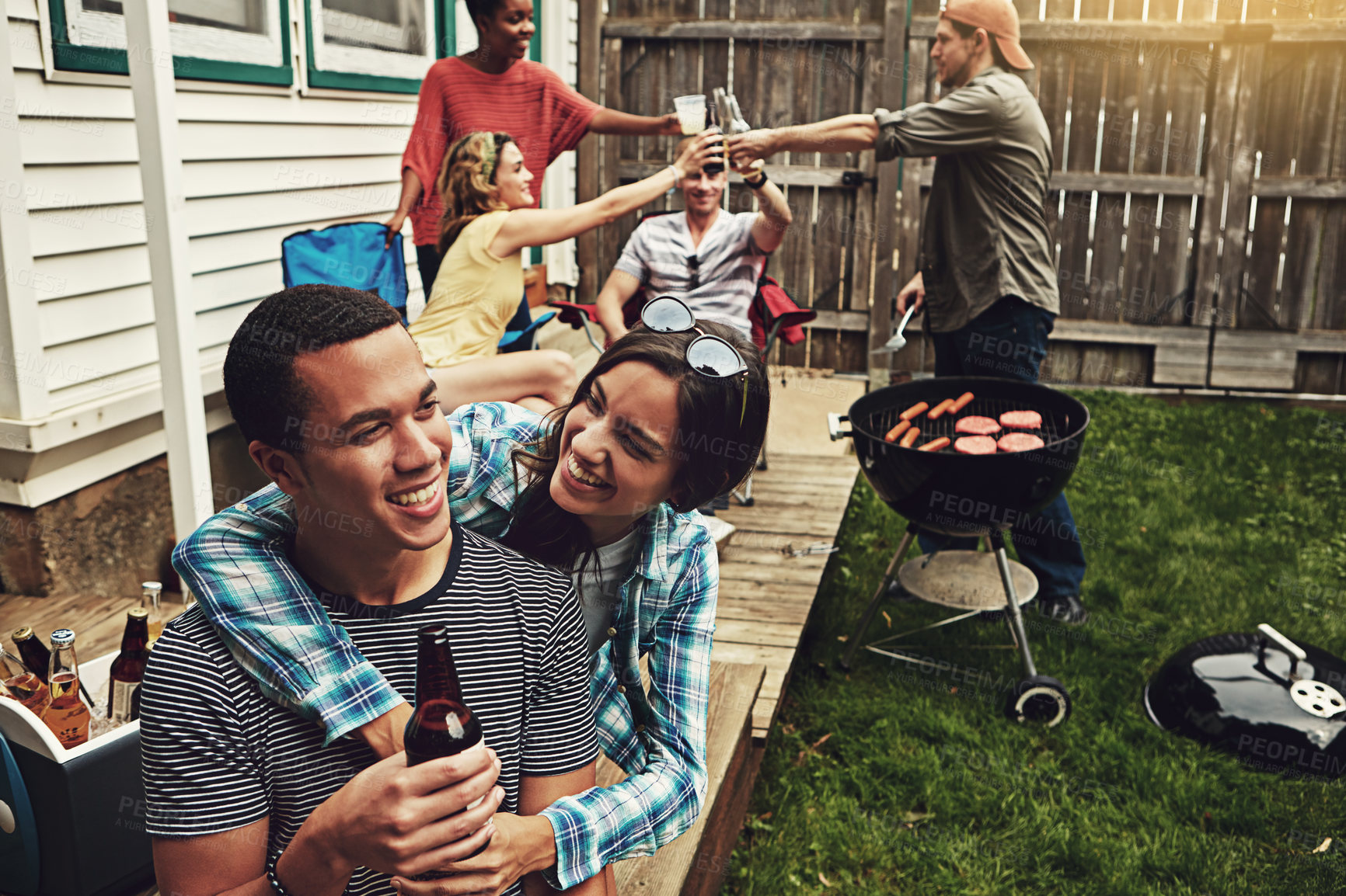 Buy stock photo Shot of a young couple enjoying a party with friends outdoors