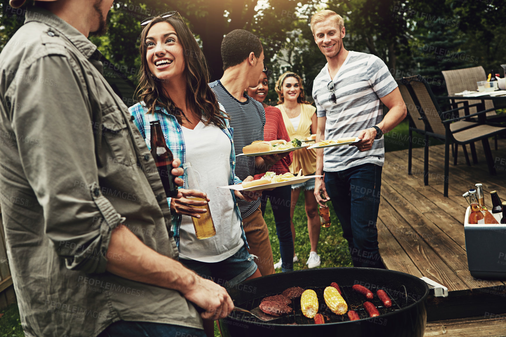 Buy stock photo Friends, barbecue and help for serving with plate in backyard with diversity, cooking or meat on fire. People, men and women with beer, drink and relax for food by bbq grill on holiday in Australia