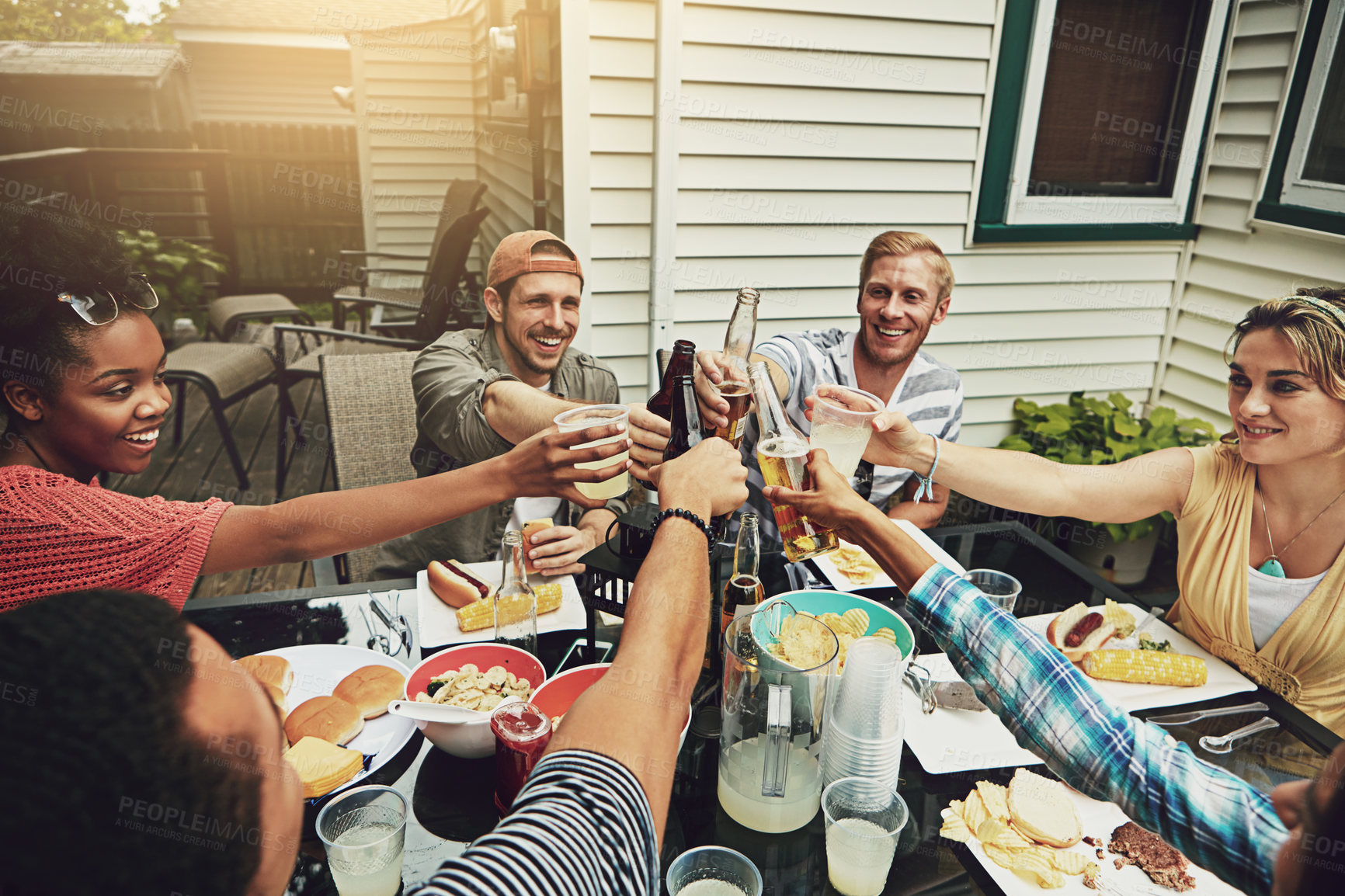 Buy stock photo Friends, toast and lunch at party, backyard or happy for food, diversity or celebration on patio. People, men and women with drink, alcohol or beer for cheers, success or excited at brunch in garden