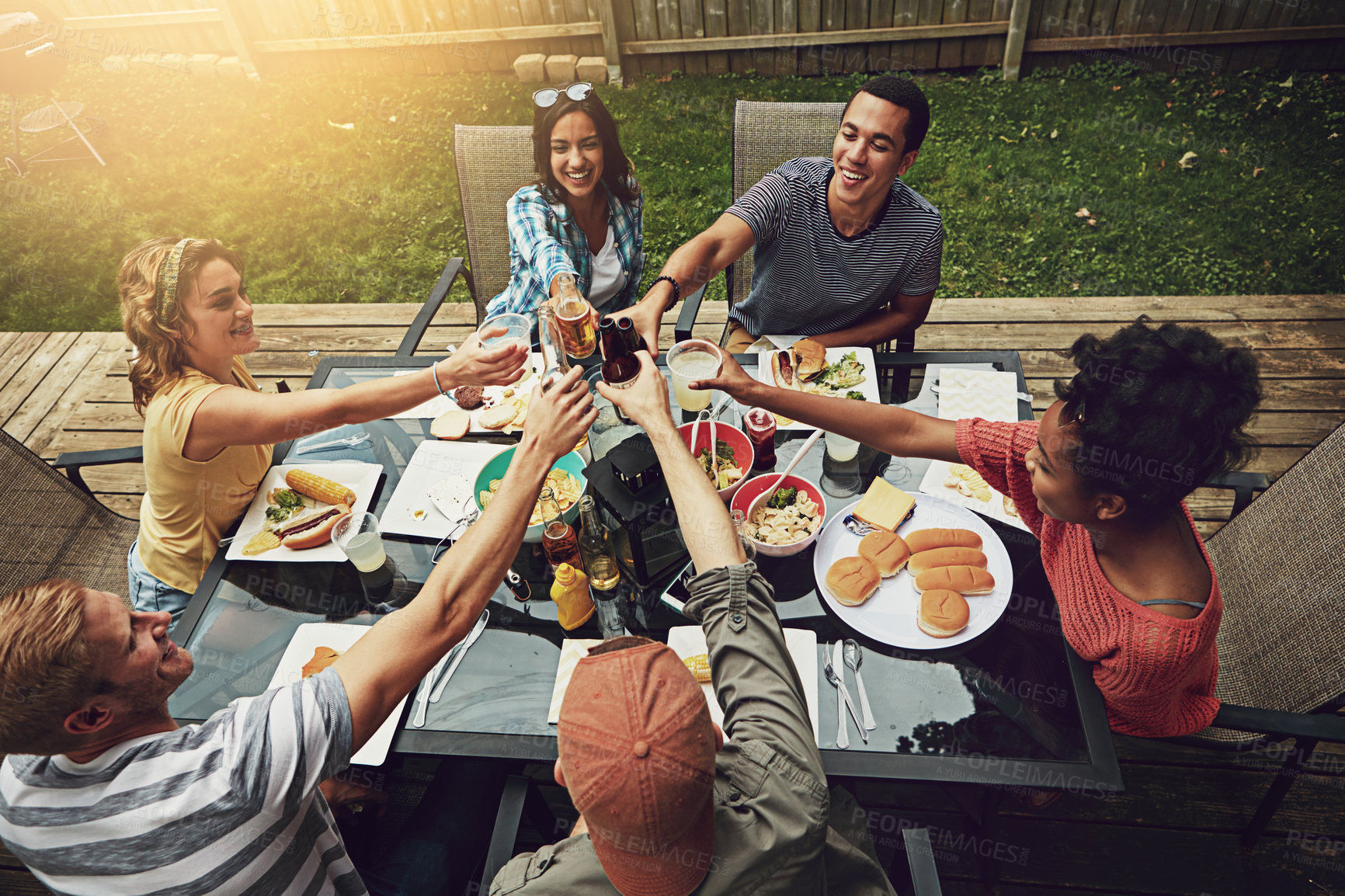 Buy stock photo Outdoor, group and friends with food, toast and  hungry for meal, celebration and party for gathering. Backyard, reunion and people together with alcohol, cheers and drinks for lunch and break