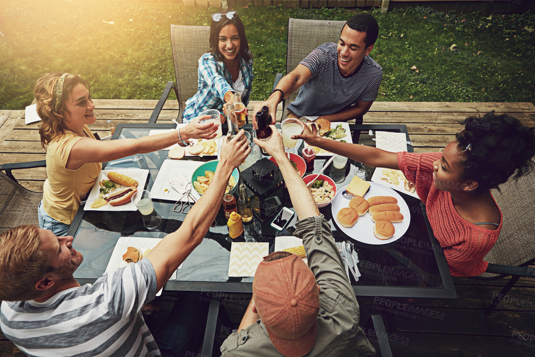 Buy stock photo Outdoor, group and friends with lunch, toast and hungry for food, celebration and party for gathering. Backyard, reunion and people together with alcohol, cheers and drinks for meal and break