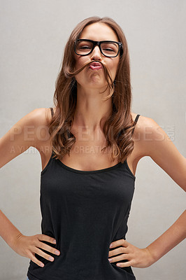 Buy stock photo Studio portrait of an attractive young woman posing with her hair over her lip against a grey background