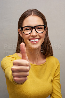 Buy stock photo Studio portrait of an attractive young woman giving you the thumbs up while posing against a grey background