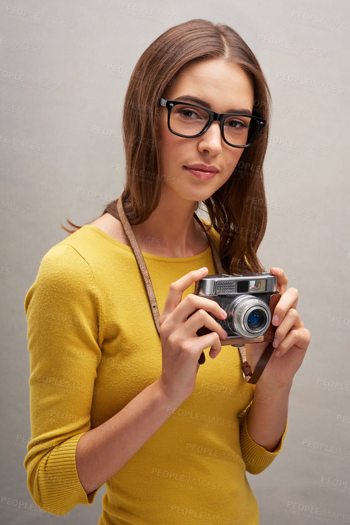 Buy stock photo Studio portrait of an attractive young female photographer posing with her camera against a grey background