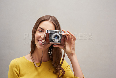 Buy stock photo Studio portrait of an attractive young female photographer posing with her camera against a grey background