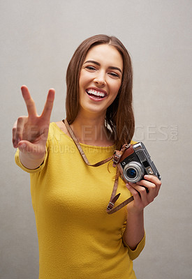 Buy stock photo Studio portrait of an attractive young female photographer posing with her camera against a grey background