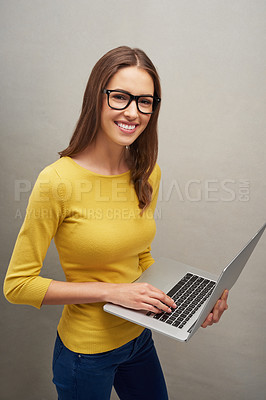 Buy stock photo Studio portrait of an attractive young woman posing with her laptop against a grey background