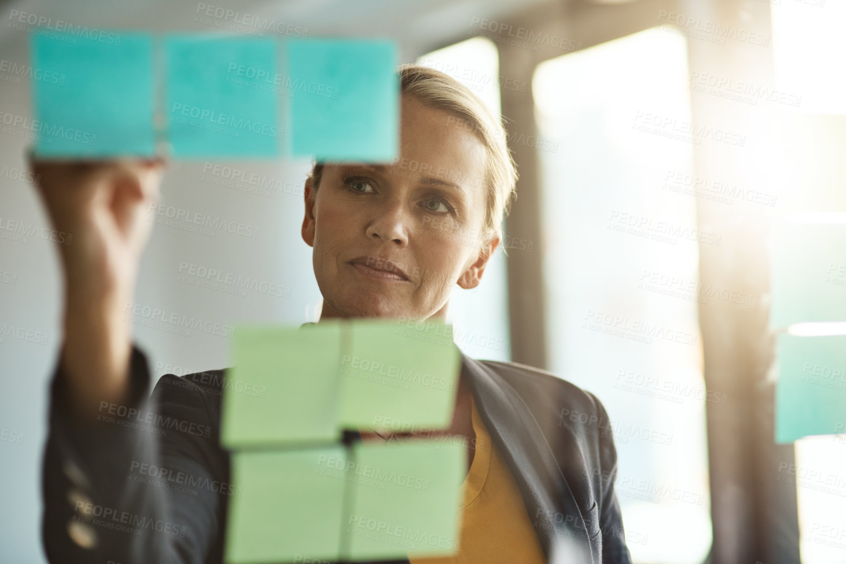 Buy stock photo Planning, sticky notes and window with business woman in office for brainstorming or development. Management, problem solving and writing with mature employee at work on glass board for vision