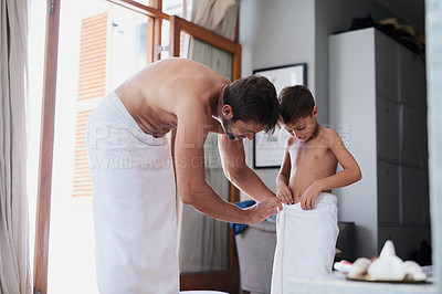 Buy stock photo Cropped shot of a handsome young man and his son wrapped in towels after a shower