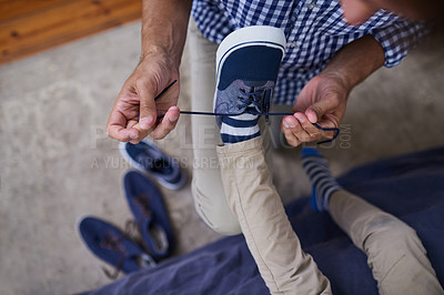 Buy stock photo High angle shot of an unrecognizable man tying his son's shoelaces at home