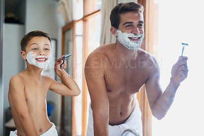 Buy stock photo Cropped shot of a handsome young man teaching his son how to shave in the bathroom