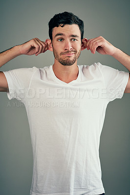 Buy stock photo Studio, ear pull and man in tshirt, playful and goofy comedian with gesture for joke in show. Grey background, funny and person with silly facial expression, hands and comic for comedy in USA