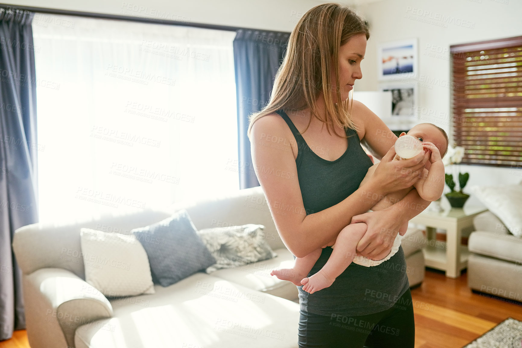 Buy stock photo Mother, milk and feeding baby in living room for growth development, nutrition or digestive health. Formula, woman parent and infant child with bottle for drinking, wellness or bonding in home
