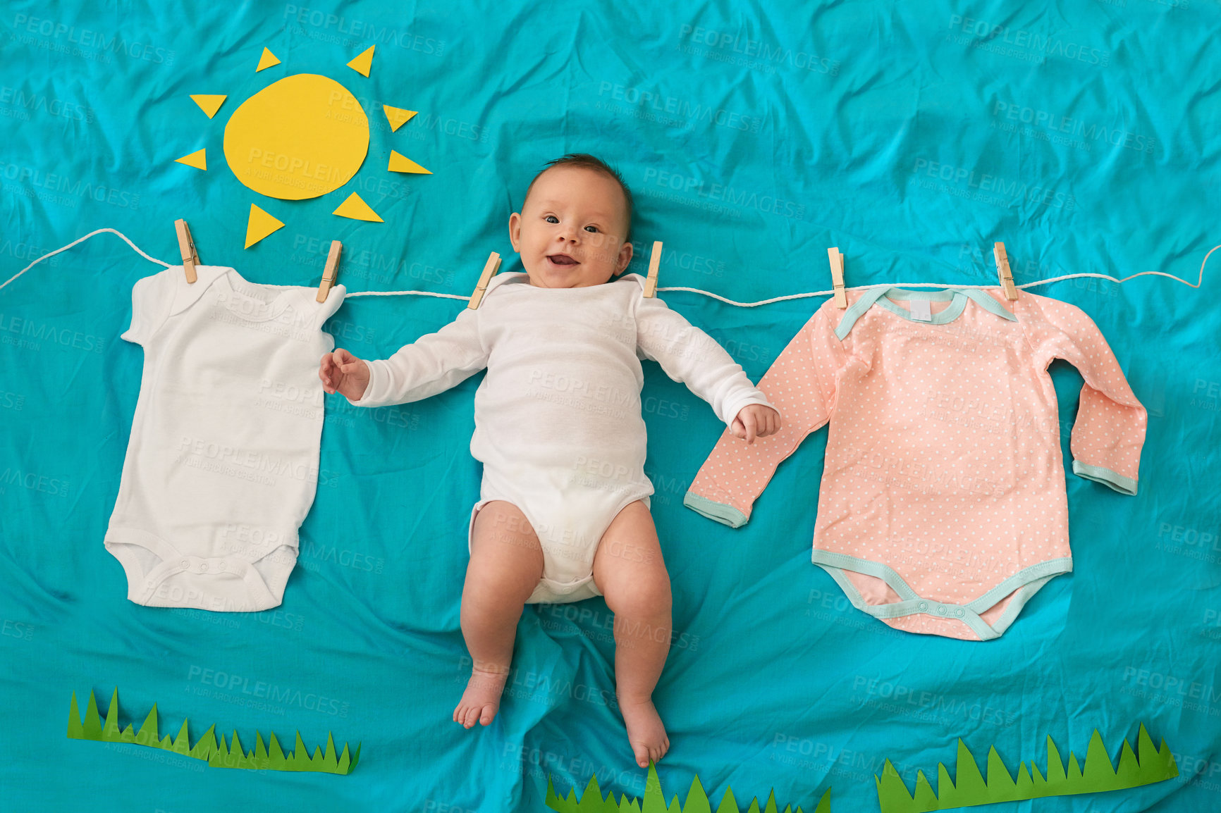 Buy stock photo Conceptual shot of a baby girl hanging on the washing line against a blue background