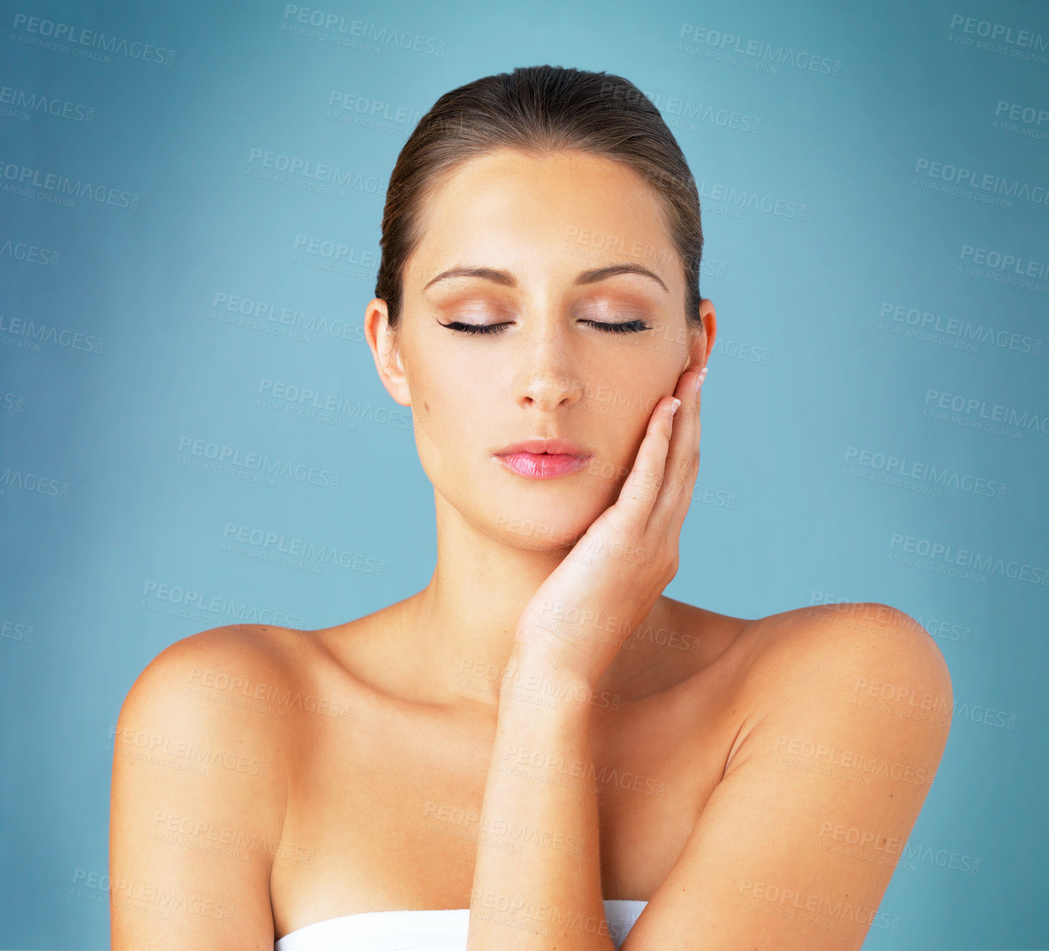 Buy stock photo Studio shot of a beautiful young woman feeling her skin against a blue background