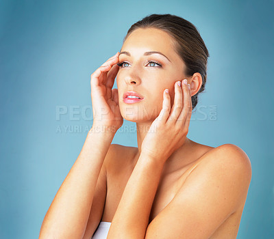 Buy stock photo Studio shot of a beautiful young woman feeling her skin against a blue background