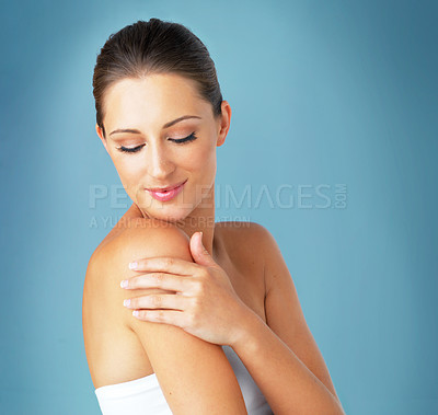 Buy stock photo Studio shot of a beautiful young woman feeling her skin against a blue background