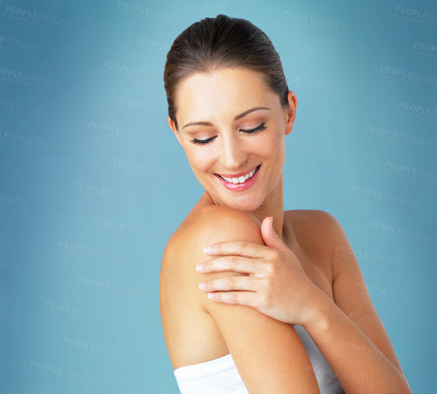 Buy stock photo Studio shot of a beautiful young woman feeling her skin against a blue background