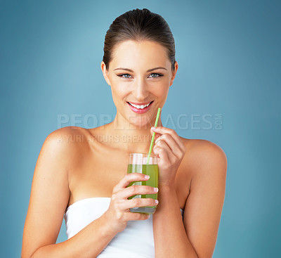 Buy stock photo Studio portrait of a beautiful young woman drinking a healthy green beverage against a blue background