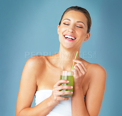 Buy stock photo Studio shot of a beautiful young woman drinking a healthy green beverage against a blue background