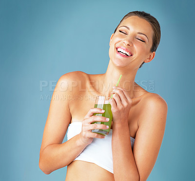 Buy stock photo Studio shot of a beautiful young woman drinking a healthy green beverage against a blue background
