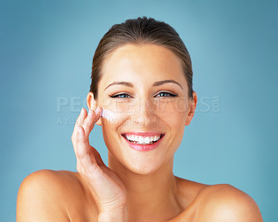 Buy stock photo Dermatology, portrait and happy woman with cream on face, cosmetics and product for makeup on blue background. Happiness, skincare and wellness for model with smile, beauty and lotion for facial glow