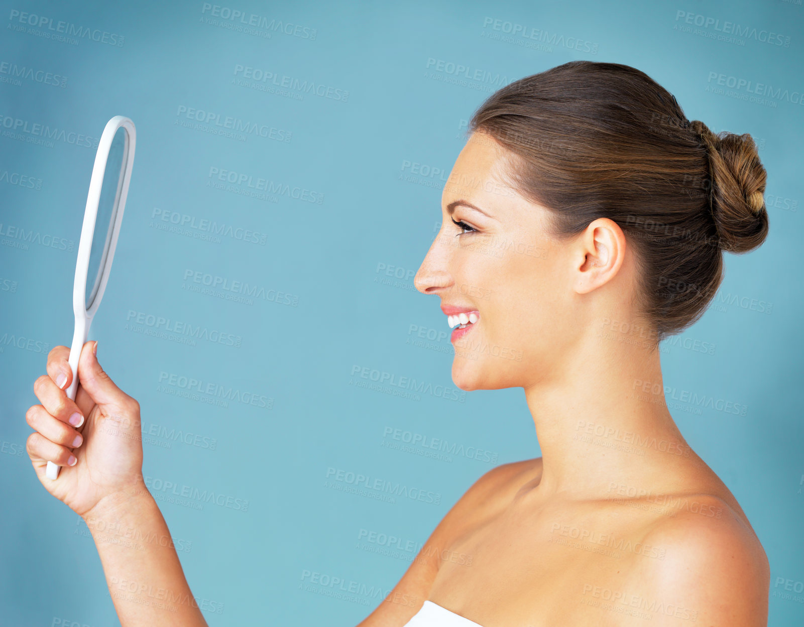 Buy stock photo Studio shot of a beautiful young woman looking at herself in the mirror against a blue background