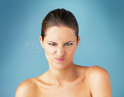 Buy stock photo Studio portrait of a beautiful young woman looking angry against a blue background