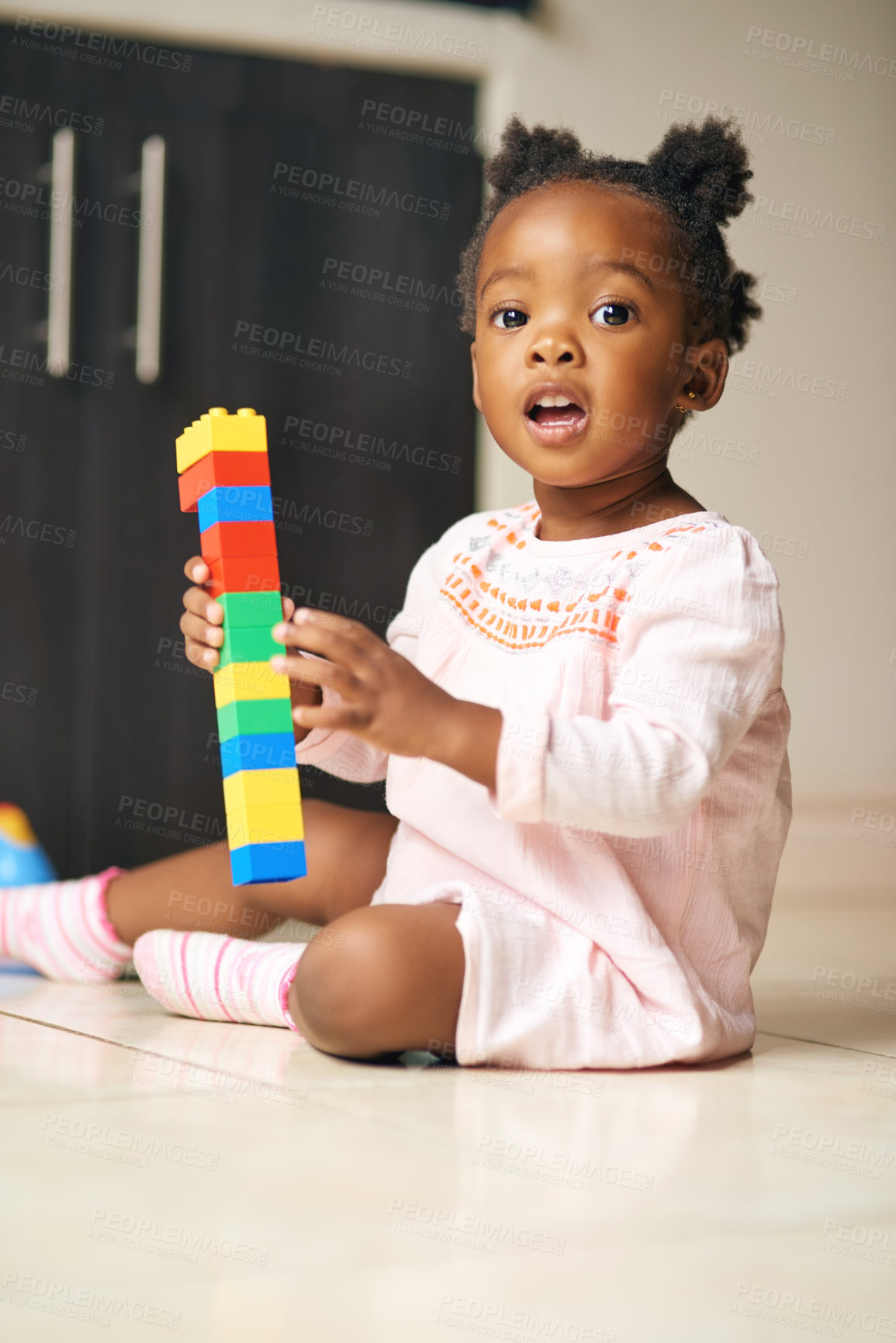 Buy stock photo Black child, portrait and little girl with blocks, toys or building for creativity or childhood development on floor at home. Young African, baby or toddler playing with colorful shapes for learning