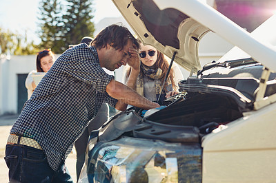 Buy stock photo Shot of a young man looking under the hood of a broken down car