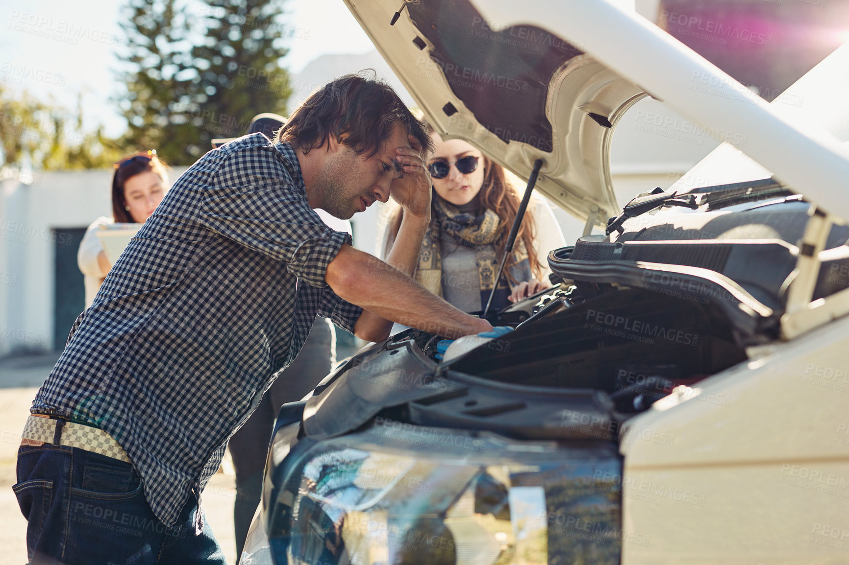 Buy stock photo Shot of a young man looking under the hood of a broken down car
