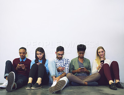 Buy stock photo Full length shot of a group of university students sitting in a corridor on campus