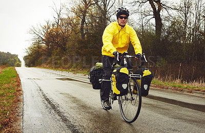 Buy stock photo Full length shot of a male cyclist enjoying a bike ride on a wet winter's morning