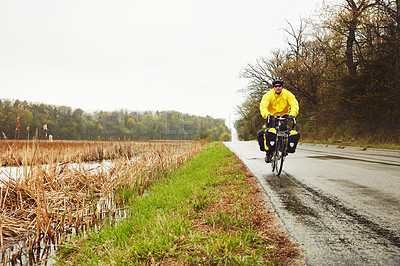 Buy stock photo Full length shot of a male cyclist enjoying a bike ride on a wet winter's morning