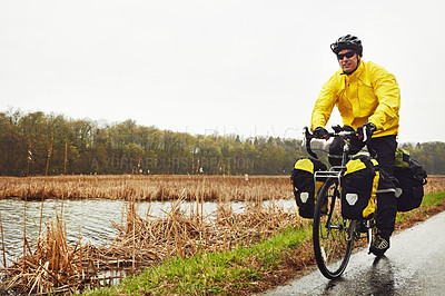 Buy stock photo Full length shot of a male cyclist enjoying a bike ride on a wet winter's morning