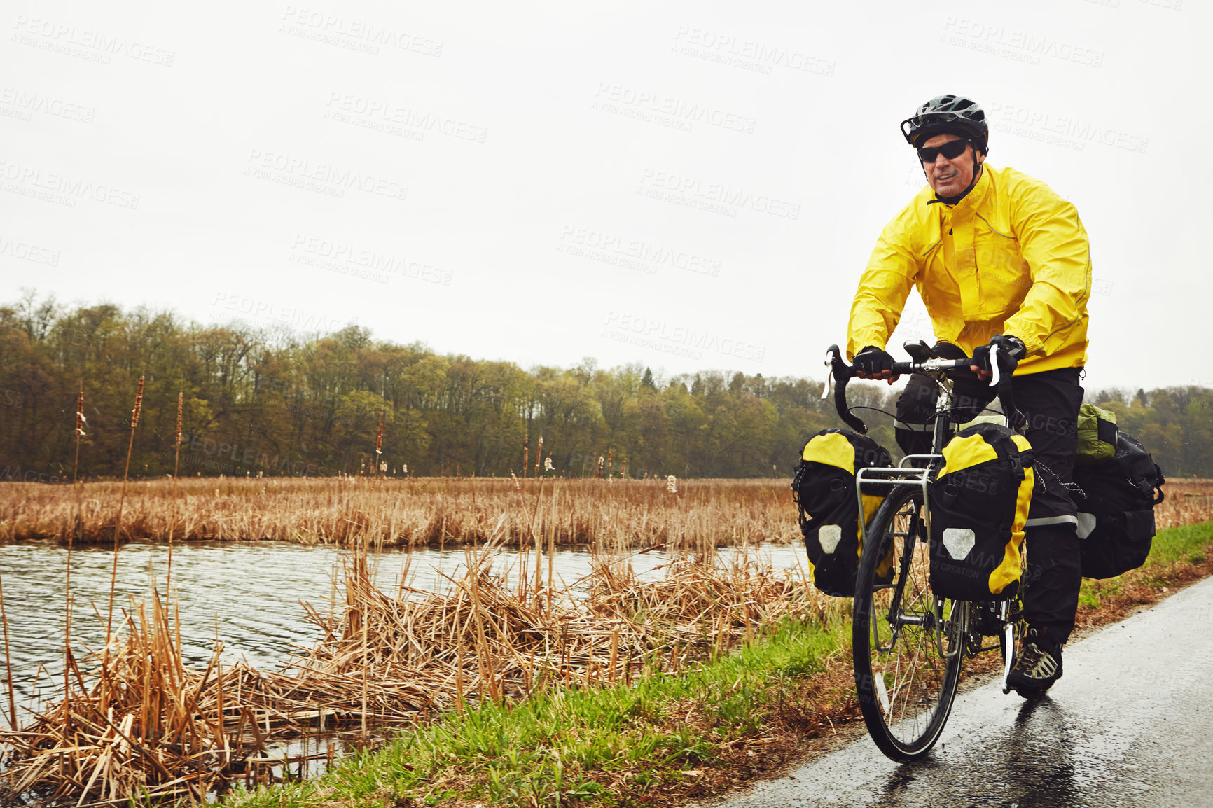 Buy stock photo Full length shot of a male cyclist enjoying a bike ride on a wet winter's morning