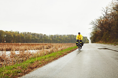 Buy stock photo Full length shot of a male cyclist enjoying a bike ride on a wet winter's morning