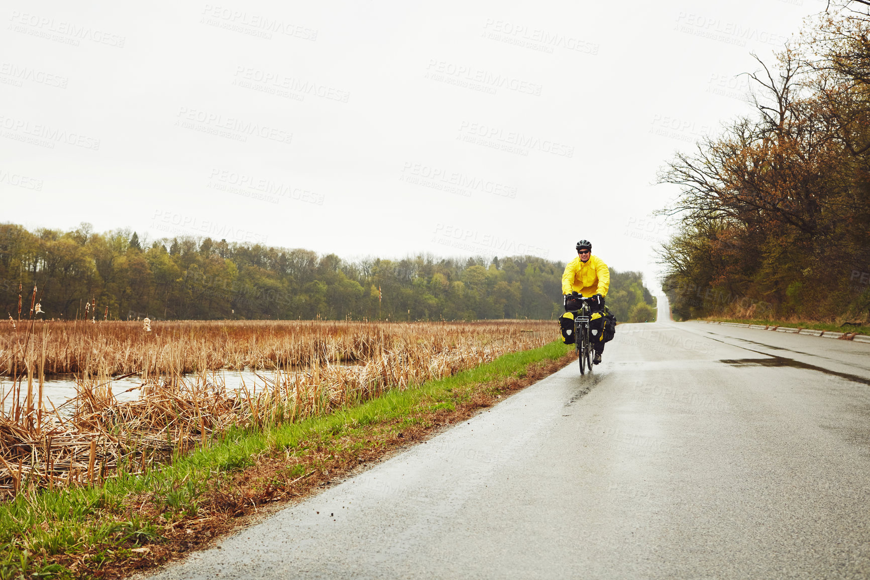 Buy stock photo Full length shot of a male cyclist enjoying a bike ride on a wet winter's morning