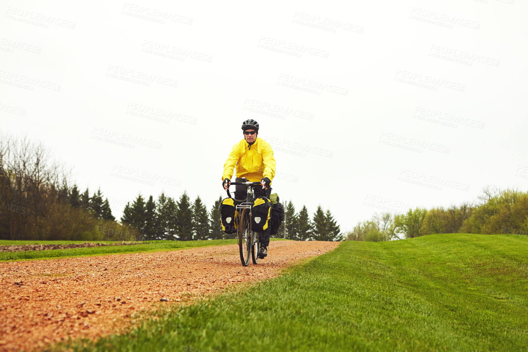 Buy stock photo Full length shot of a male cyclist enjoying a bike ride on a wet winter's morning