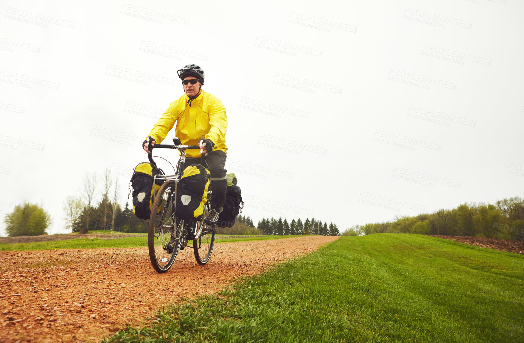 Buy stock photo Full length shot of a male cyclist enjoying a bike ride on a wet winter's morning