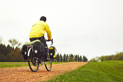 Buy stock photo Rearview shot of a male cyclist enjoying a bike ride on a wet winter's morning